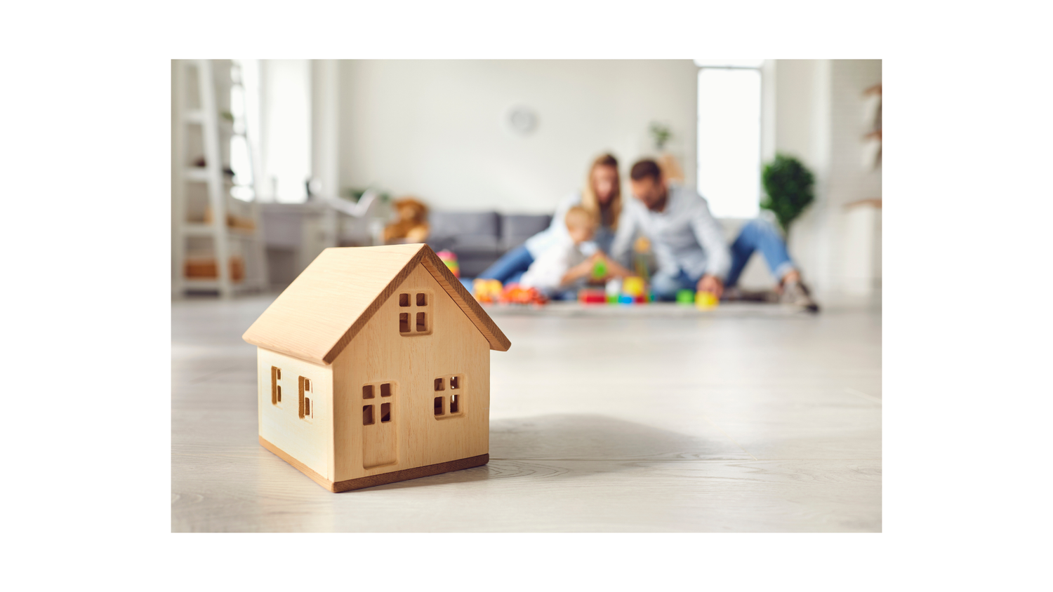 Casita de madera en primer plano con familia jugando al fondo, símbolo de hogar y crianza consciente.